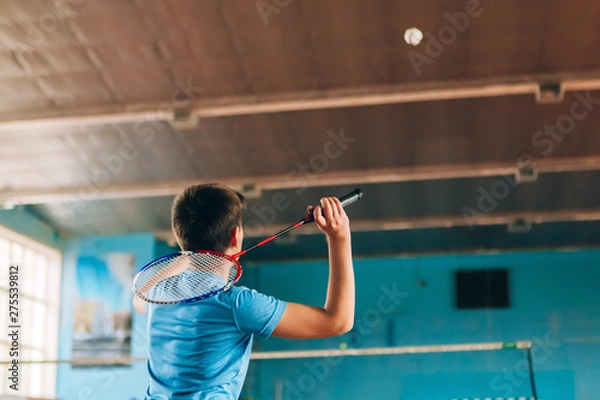 Fototapeta Badminton court with players. Tennis player with a racket. Badminton activity. Sports game of success. Happy kid playing badminton. The child beats the shuttle with a racket.