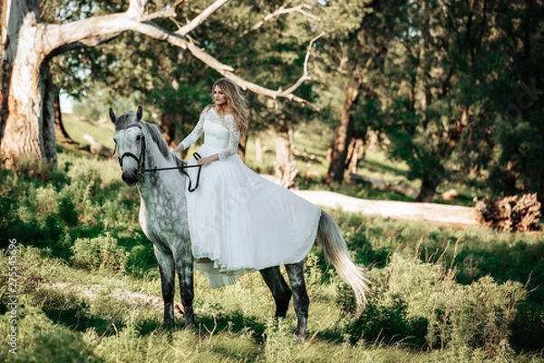 Fototapeta Beautiful and stunning bride, riding a horse in the nature