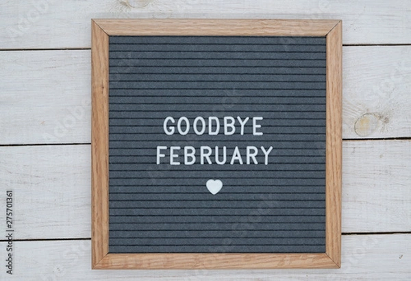 Fototapeta text in English goodbye February and a heart sign on a gray felt Board in a wooden frame