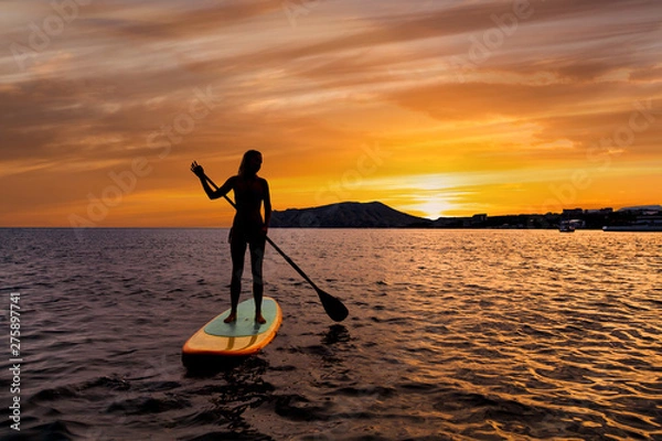 Obraz Stand up paddle boarding on a quiet sea with warm summer sunset colors.
