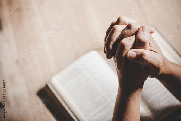 Fototapeta Duchowość i religia, Ręce złożone do modlitwy na Biblii Świętej w kościelnej koncepcji wiary.