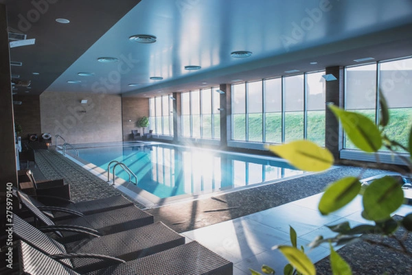 Fototapeta beautiful indoor pool with Jacuzzi with rattan furniture and large panoramic Windows, lighting and finished in loft style