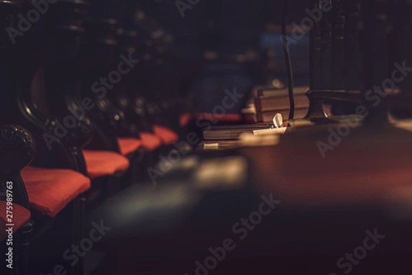 Fototapeta A dark and moody shot of a single bible in focus in a large Cathedral