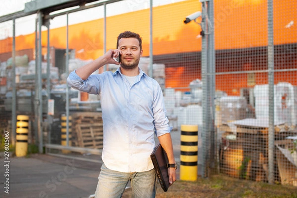 Fototapeta Portrait of sales representative. Logistics manager calling to his business partner to have a deal. Concept of warehouse outdoor and transportation services. .