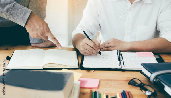 Fototapeta Student reading textbook for test together in library.
