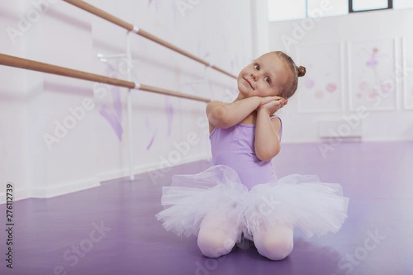 Obraz Cute little ballerina dancing at ballet school, copy space. Adorable little girl in ballet outfit practicing at dance class. Children, kids development concept