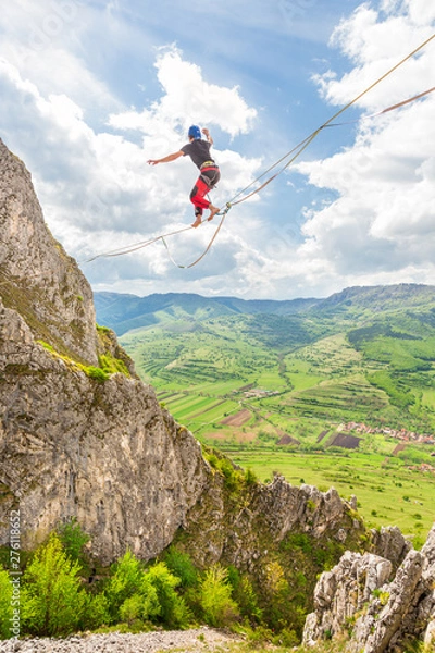 Obraz Young slackliner man balancing on a slackline betweend two rocks. Highline with a beautiful natural landscape behind
