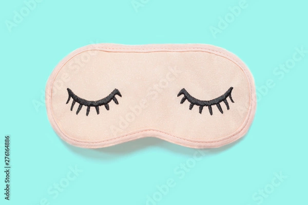 Fototapeta Pastel pink sleep mask with closed eyes embroidered on it with eyelashes on turquoise background. Top view, flat lay. Concept of vivid dreams. Accessories for girls and young women. Minimal style