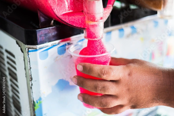 Fototapeta Human hand serving slushy drink from slushy  machine