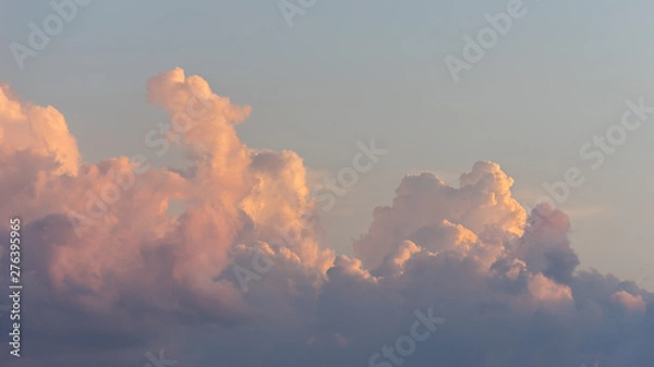 Fototapeta Close up view of beautiful colored cumulus fluffy clouds with pink and purple hues in the blue sky at sunset background