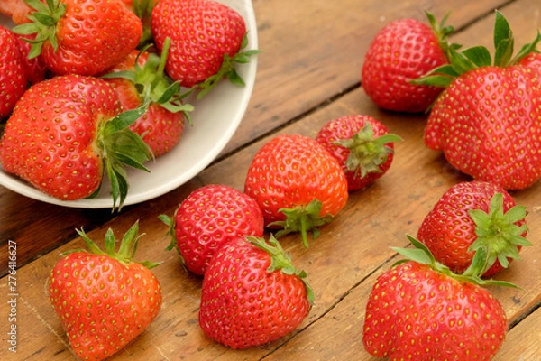 Fototapeta strawberries in a bowl and on a wooden table top