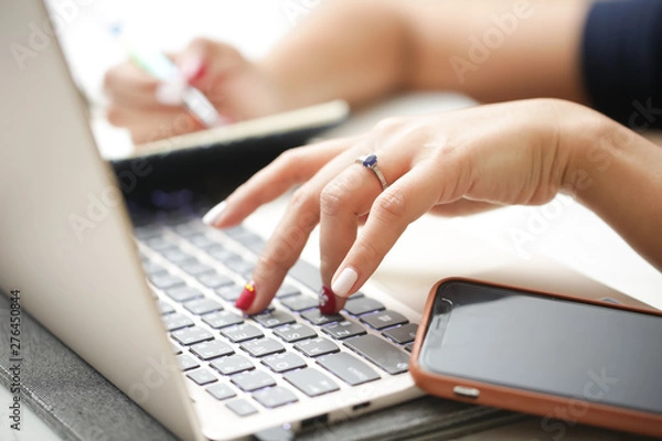 Fototapeta Woman sitting at desk and working at computer close up in hands.
