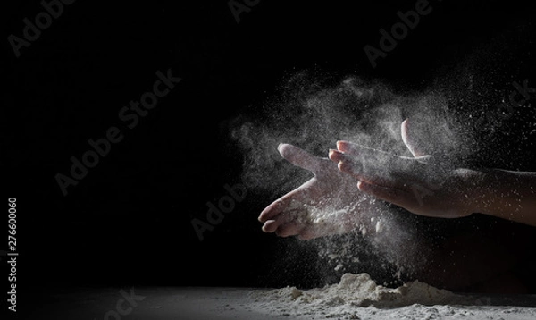 Fototapeta woman chef hand clap with splash of white flour and black background with copy space.