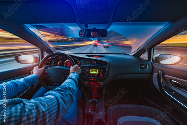 Fototapeta A man is driving along the highway. Evening time during the rain.