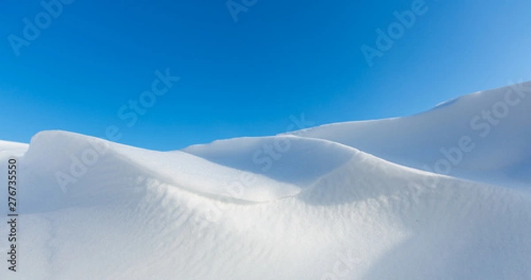 Fototapeta Snow dunes caused by drifting snow and the wind in winter with bright sunlight