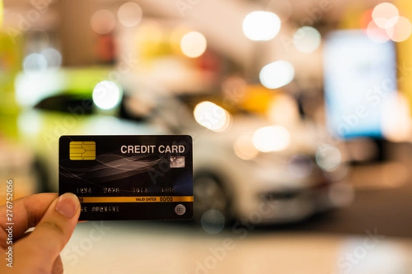 Obraz Hand holding credit card with blur car showroom in shopping mall , shopping and retail,  Payment by credit card for buy new car concept.