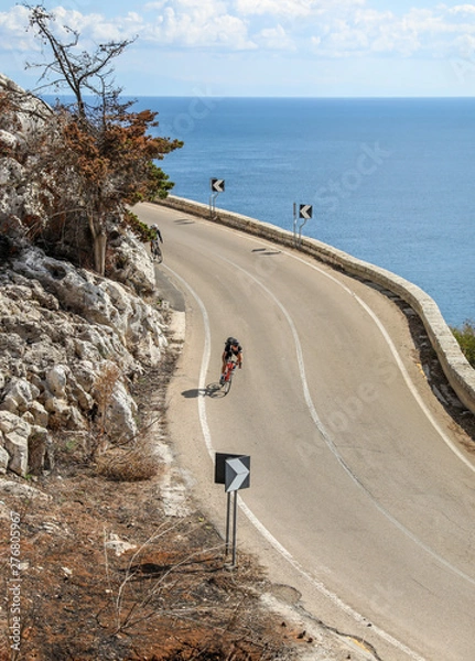 Obraz A cyclist coming around the corner on a coastal road in Puglia, Italy. 