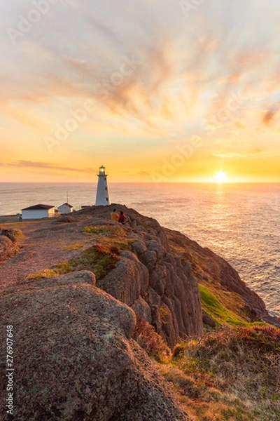 Fototapeta Beautiful sunrise over a white lighthouse sitting at the edge of a rocky cliff. Cape Spear National Historic Site, St Johns Newfoundland. 