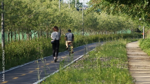 Obraz 시대의 변화 - 노인은 자전거를 타고, 젊은이는 퀵보드를 탄다.