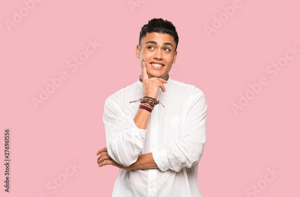 Fototapeta Young man thinking an idea while looking up on colorful background