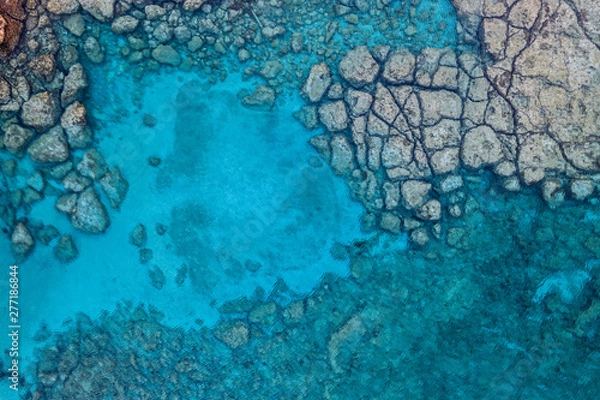 Obraz An aerial view of the beautiful Mediterranean Sea, with a rocky shore, where you can see the textured underwater corals and the clean turquoise water of Protaras, Cyprus