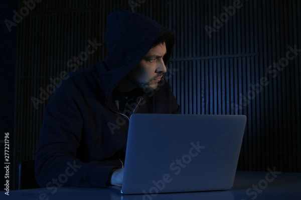 Fototapeta Man using laptop in dark room. Criminal offence