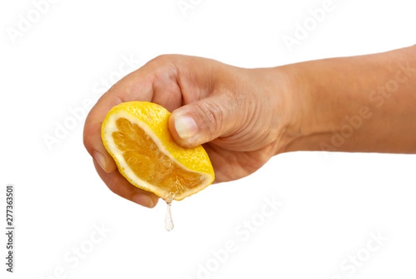Obraz Women's hand squeezing a half of fresh lemon yellow on a white background.