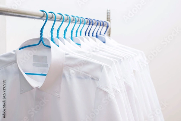 Fototapeta White shirts hanging on rack in a row