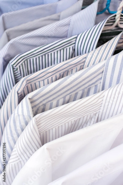 Fototapeta Men shirts hanging on rack in a row, Selective Focus