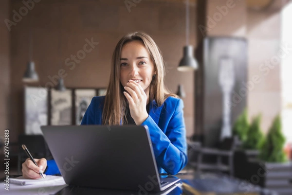 Obraz Business woman with laptop and notebook looks thoughtfully