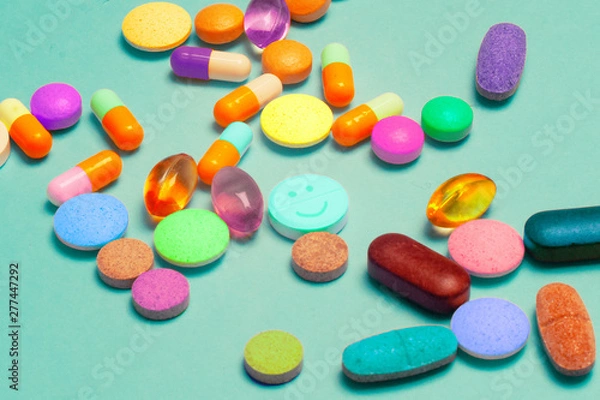 Fototapeta Pills on a blue background. Assorted pharmaceutical medicine pills, tablets and capsules, health macro. Heap of various pills on color background. LSD pills drugs, bright Psychedelic pill.