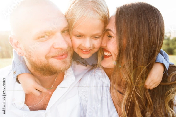 Fototapeta Happy family with blonde daughter smiling and hugging in nature.