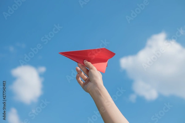 Obraz Woman hand holding a red paper rocket with a bright blue background.
