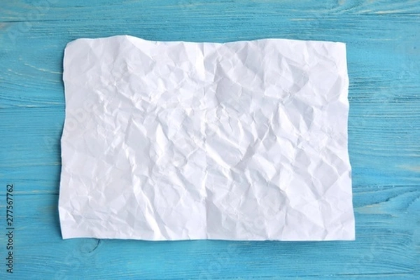 Obraz crumpled paper on blue wooden background for design banner or card, selective focus. Clear textured obsolete page with empty space for image or text on turquoise backdrop. Mockup concept 