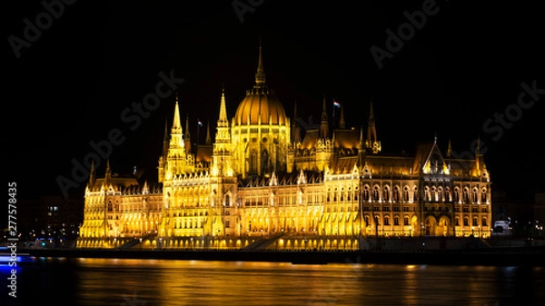 Obraz Cityscape of Budapest with bright parliament illuminated and reflection in Danube river. Pink and purple colors of sky reflecting in water during sunset.