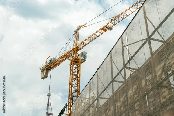 Fototapeta Reconstruction of the old building. Yellow Crane. Restoration of the building against the sky with clouds, view from the bottom up. Georgia, Tbilisi