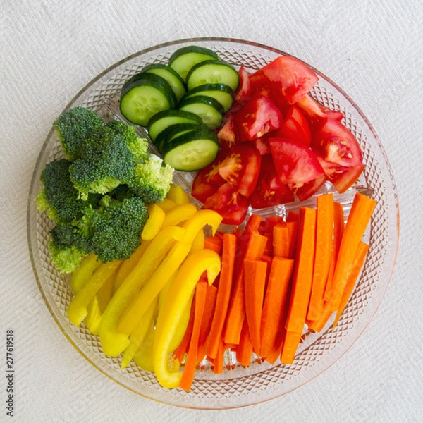 Fototapeta Fresh cut up vegetables in a platter; appetizing broccoli, carrots, tomatoes, peppers and cucumbers displayed as a rainbow