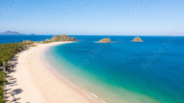 Fototapeta Wide tropical beach with white sand and small islands, top view. Nacpan Beach El Nido, Palawan. Seascape in clear weather, view from above.