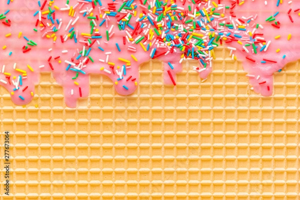 Fototapeta golden waffle texture with pink icing and sprinkles, background for your design