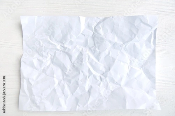 Fototapeta crumpled paper on white background for design banner or card, selective focus. Clear textured page with empty space for image or text on wooden white backdrop. Mockup concept 