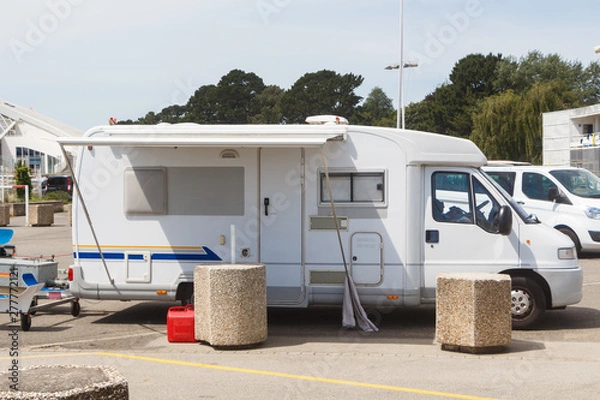 Obraz White camper with awning parks in a parking
