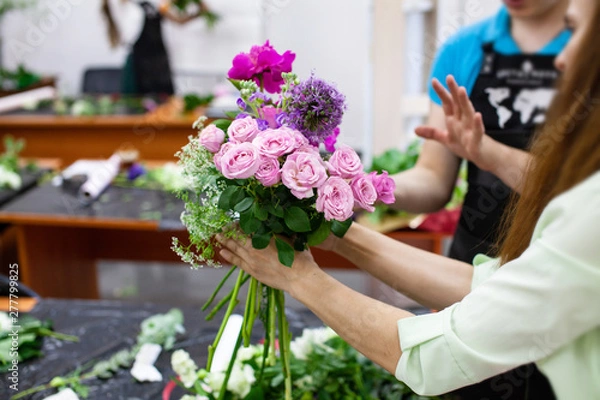 Fototapeta Female florist create a bouquet at workplace. Floristics workshop. Making beautiful flower bouquets and floral decorations..