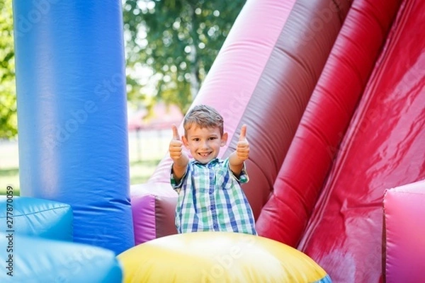 Obraz having fun on the slide in the fun park in bouncy castle climbing stairs
