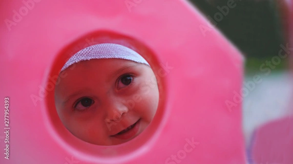 Obraz Funny little boy look through the hole in rose plastic fence