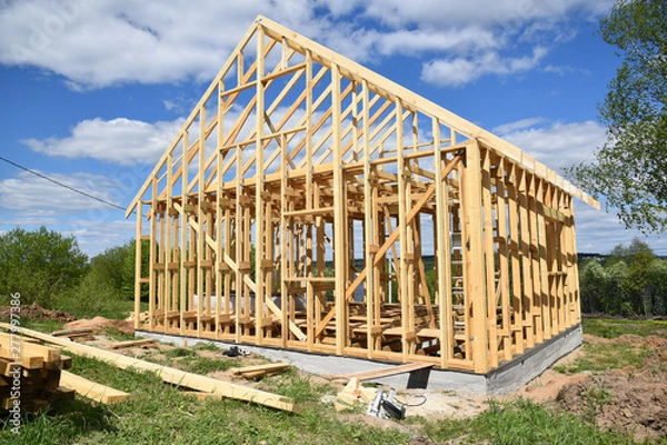 Fototapeta Wood frame residential building under construction.Building construction, wood framing structure at new property development site.new home currently under construction against blue sky.mortgage, loan.