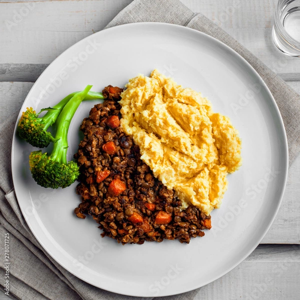 Obraz Plate of shepherd’s pie on a white wooden table. Meal made of smashed potatoes, minced meat, lentil and vegetables. Top view, above shot.