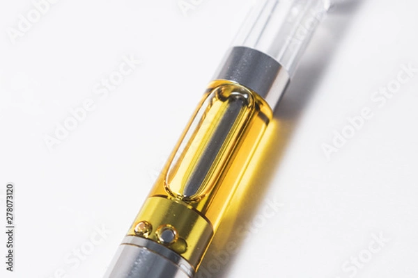 Obraz Cannabis oil liquid extract up-close in plastic cartridge, to vape and inhale the medicinal cannabinoids THC & CBD found in marijuana plants. Macro shot isolated on white background.