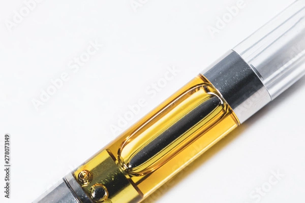Obraz Cannabis oil liquid extract up-close in plastic cartridge, to vape and inhale the medicinal cannabinoids THC & CBD found in marijuana plants. Macro shot isolated on white background.