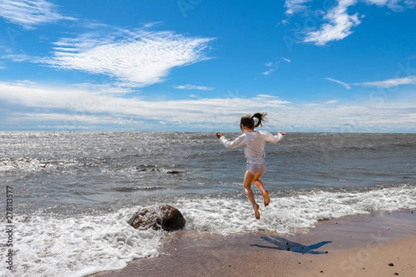 Fototapeta girl frolicking on the ocean in Sunny weather, jumping over the waves.