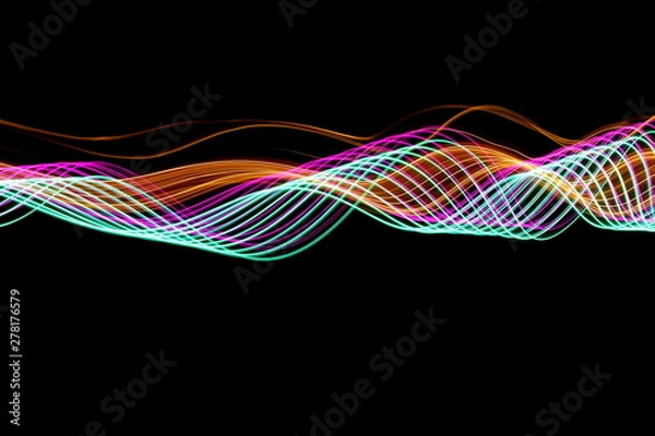 Obraz Long exposure photograph of neon purple, green and metallic gold colour in an abstract swirl pattern against a black background. Light painting photography.